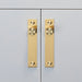 Brass Buster + Punch Cross furniture knob plates installed on cabinet doors