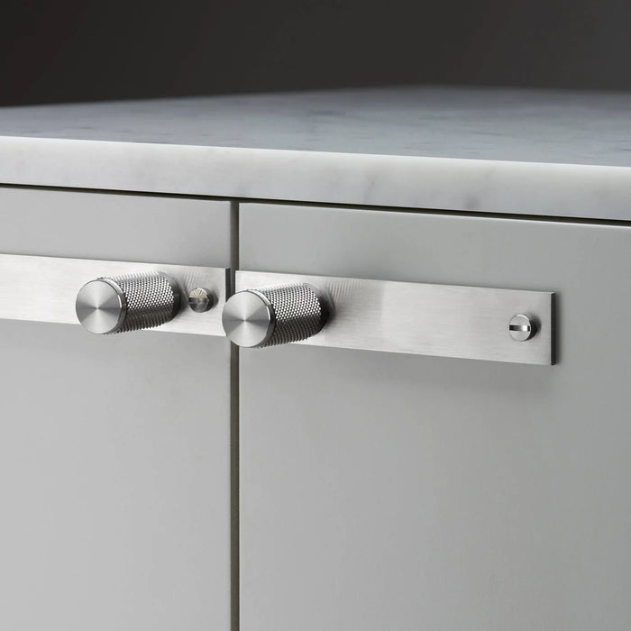 Close-up of Buster + Punch Cross Steel furniture knob plate on cabinetry