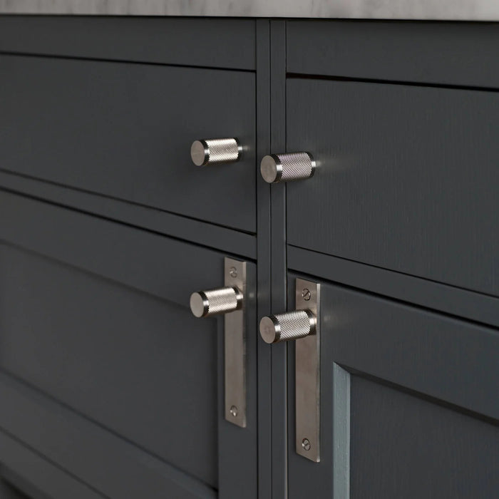 Steel Buster + Punch Cross furniture knob plates on dark cabinetry