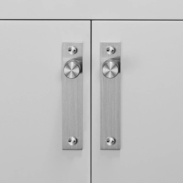 Steel Buster + Punch Cross furniture knob plates mounted on cabinet doors