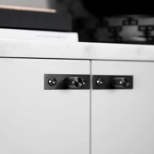 Buster + Punch Furniture Knob Plate Linear in Gun Metal on white cabinet doors