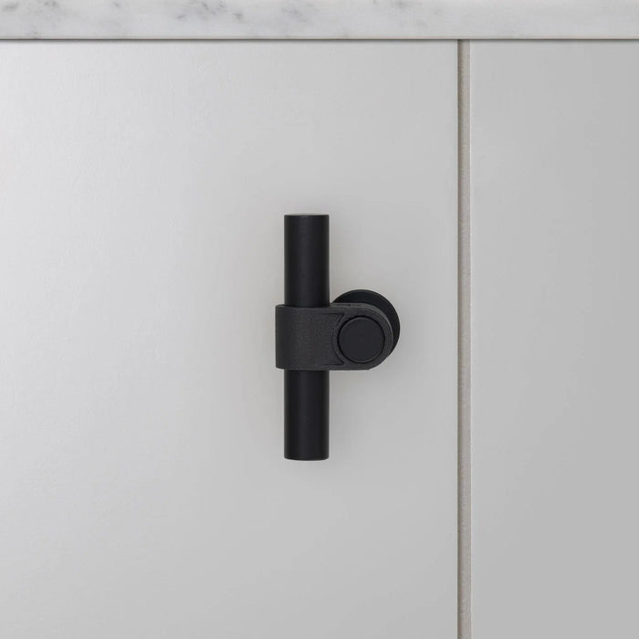 Front view of Buster + Punch T-Bar CAST cabinet knob in Welders Black finish mounted on cabinet door