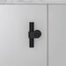 Front view of Buster + Punch T-Bar CAST cabinet knob in Welders Black finish mounted on cabinet door
