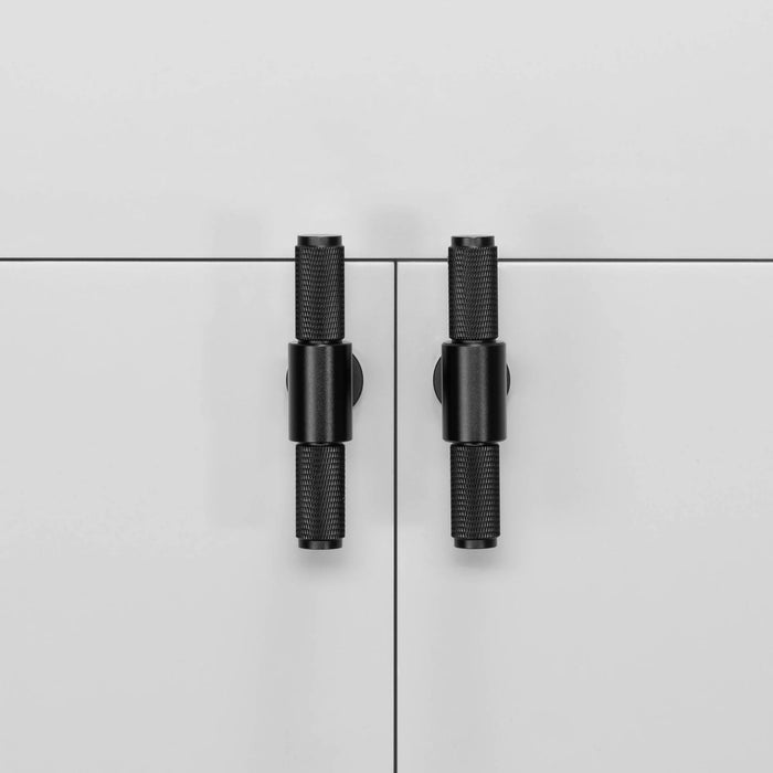 Pair of Buster + Punch T-Bar Cross cabinet knobs in Black finish mounted on cabinetry