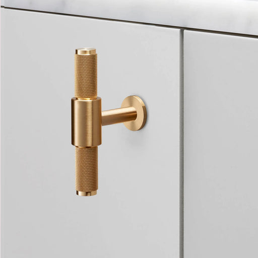 Buster + Punch T-Bar Cross cabinet knob in Brass finish mounted on white cabinetry