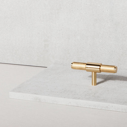 Buster + Punch T-Bar Cross cabinet knob in Brass finish displayed in a modern luxury interior setting