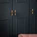 Brass Buster + Punch T-Bar Cross knobs installed on dark wardrobe doors