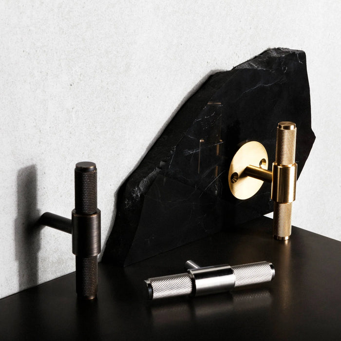 Buster + Punch T-Bar Cross cabinet knobs displayed in Brass, Smoked Bronze , and Steel finishes