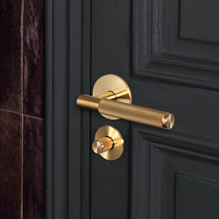 Buster + Punch Cross thumbturn lock in brass finish installed on dark interior door