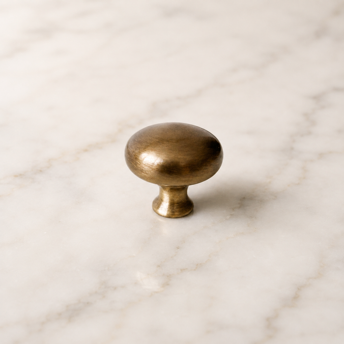 CBH 502 Classic Dome Cabinet Knob in Antique Brass displayed on a marble surface