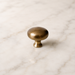 CBH 502 Classic Dome Cabinet Knob in Antique Brass displayed on a marble surface