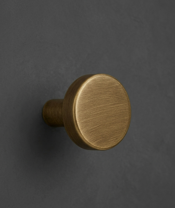 CBH 503 Minimalist Round Cabinet Knob in Antique Brass finish installed on dark cabinetry