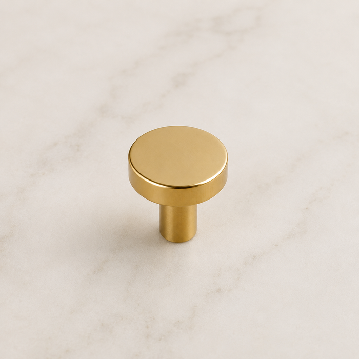 CBH 503 Minimalist Round Cabinet Knob in Bright Brass finish displayed on marble