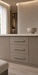 Häfele Elite Leather cabinet handles in matte nickel finish with Oyster faux leather inserts installed on a modern vanity with three drawers.