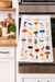 Mushroom alphabet kitchen towel hanging on oven in modern kitchen with colorful botanical mushroom illustrations