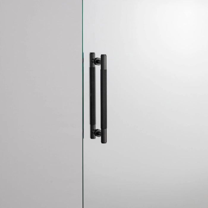 Smoked Bronze Buster + Punch Double-Sided Pull Bar Cross installed on glass door