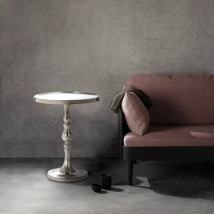 Renwil Romina raw nickel accent table styled beside a sofa in a modern luxury living room