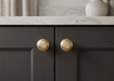 Richelieu 7903 cabinet knob set of 2 installed on dark cabinetry in polished brass finish