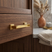 Richelieu 8645 transitional metal cabinet pull in brushed aurum gold installed on a wood cabinet