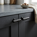 Richelieu 8997 black cabinet knobs installed on a dark cabinet