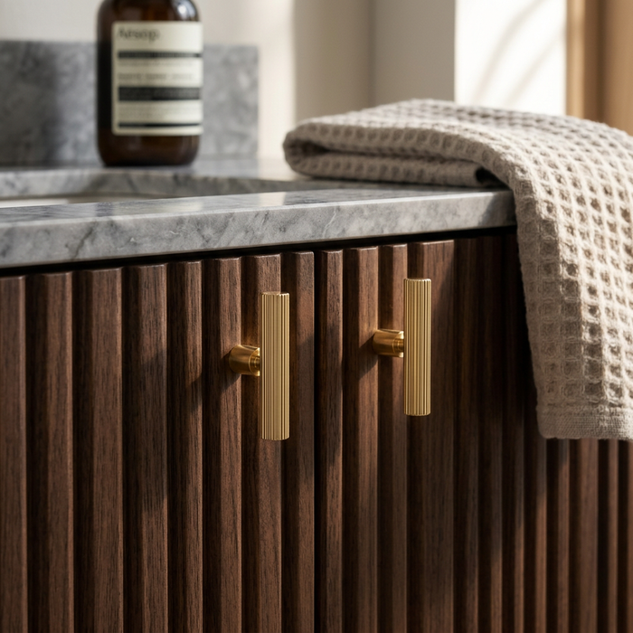 Richelieu 9730 fluted cabinet knob set of 2 in polished gold on textured wood cabinet in bathroom setting