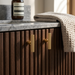 Richelieu 9730 fluted cabinet knob set of 2 in polished gold on textured wood cabinet in bathroom setting