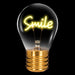 Smile neon LED light bulb with warm white filament glowing on black background